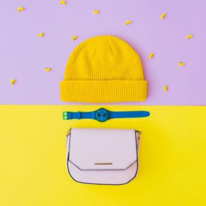 Fashionable flat lay set with yellow beanie hat, blue watches and pink bag
